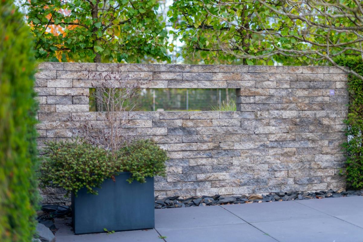 Moderne Natursteinmauer mit Pflanzkübel