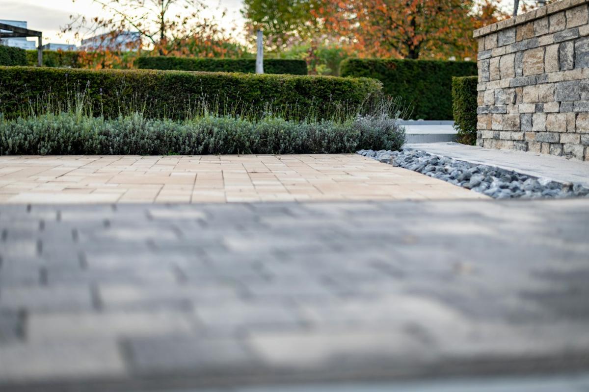 Moderner Gartenweg mit Natursteinmauer und Hecken